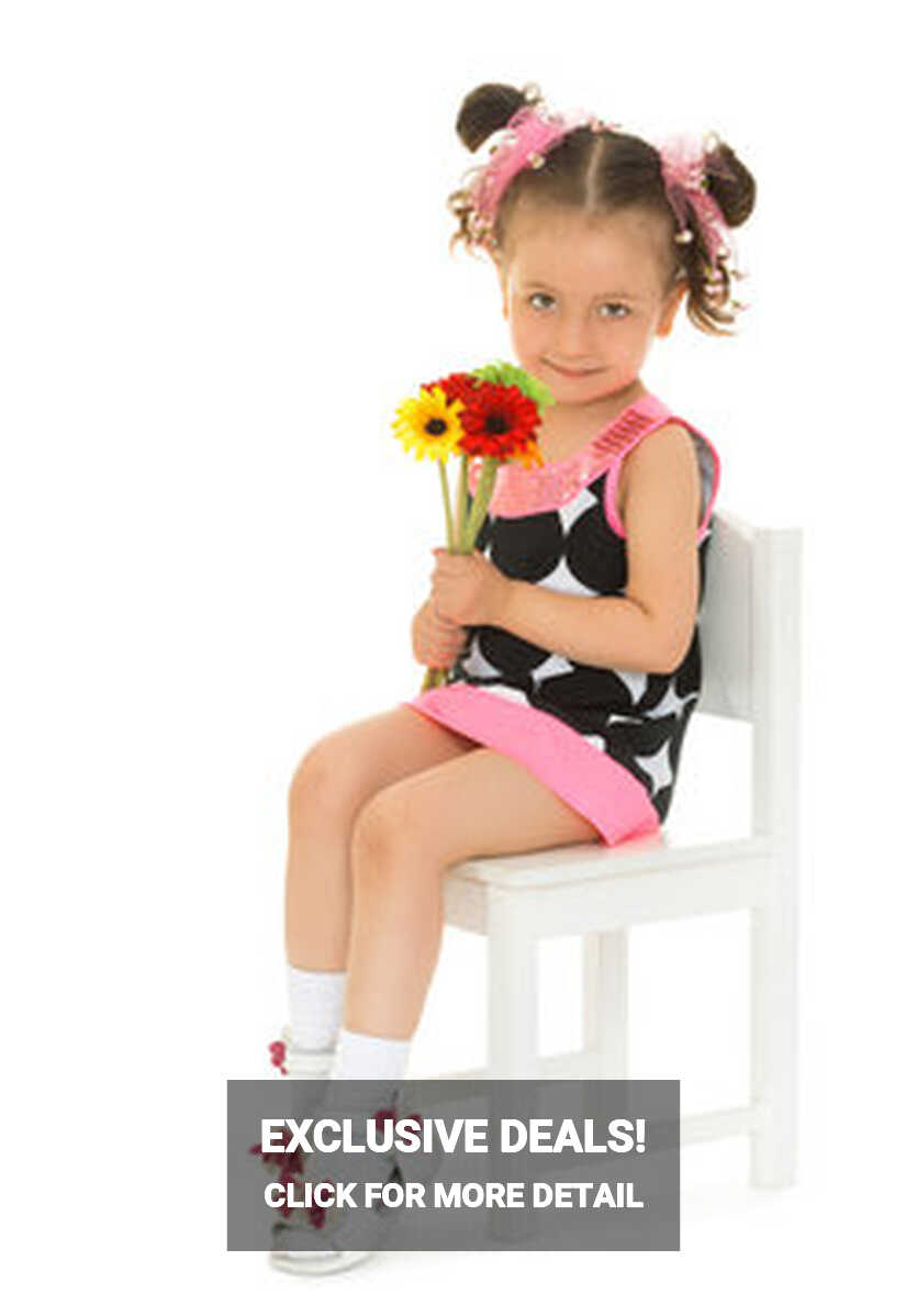 Cute little girl dressed in a short dress sits on a chair, and ...