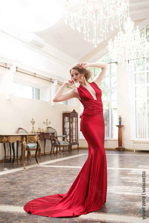 Beautiful woman in an elegant red dress in a classic interior ...