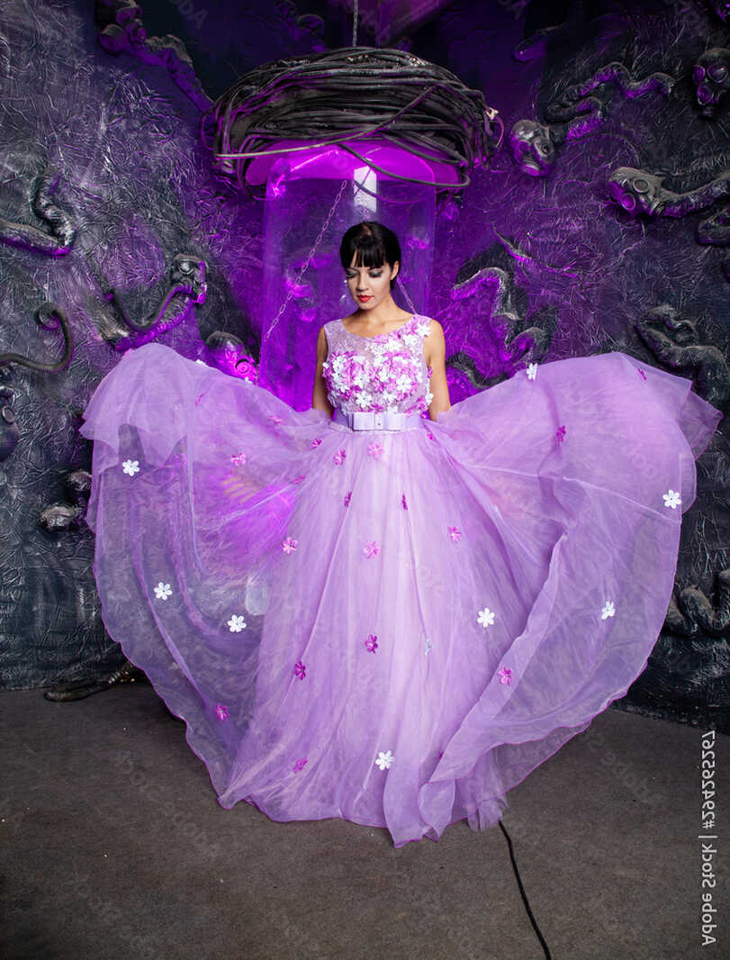 beautiful young woman in purple long evening dress near glass ...